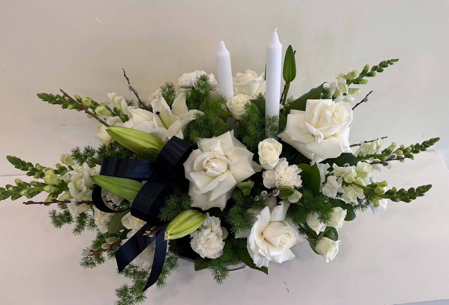 Elegant funeral flower design with three white taper candles โ same-day delivery Aurora & GTA