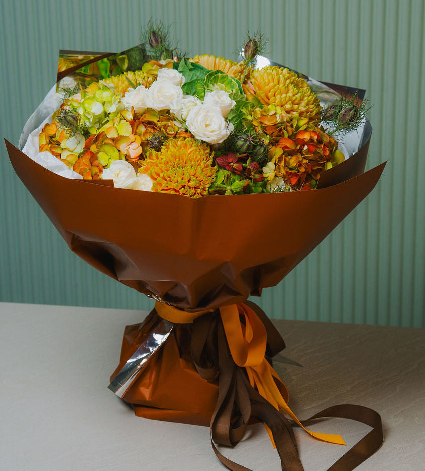 Luxury autumn bouquet with golden chrysanthemums, ivory roses, and brown wrapping
