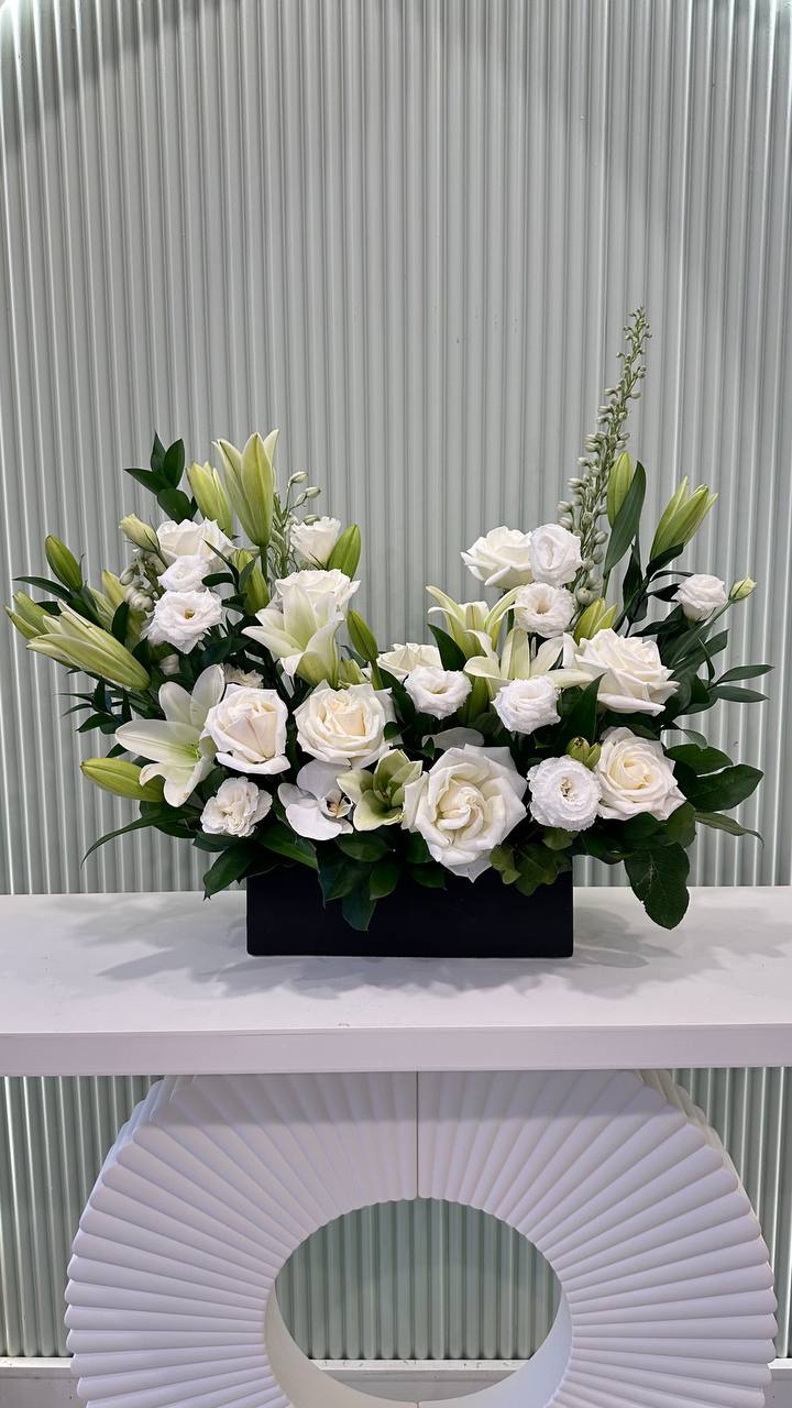 All white floral design with tall vertical black vase handcrafted by Lotus Land Flower shop