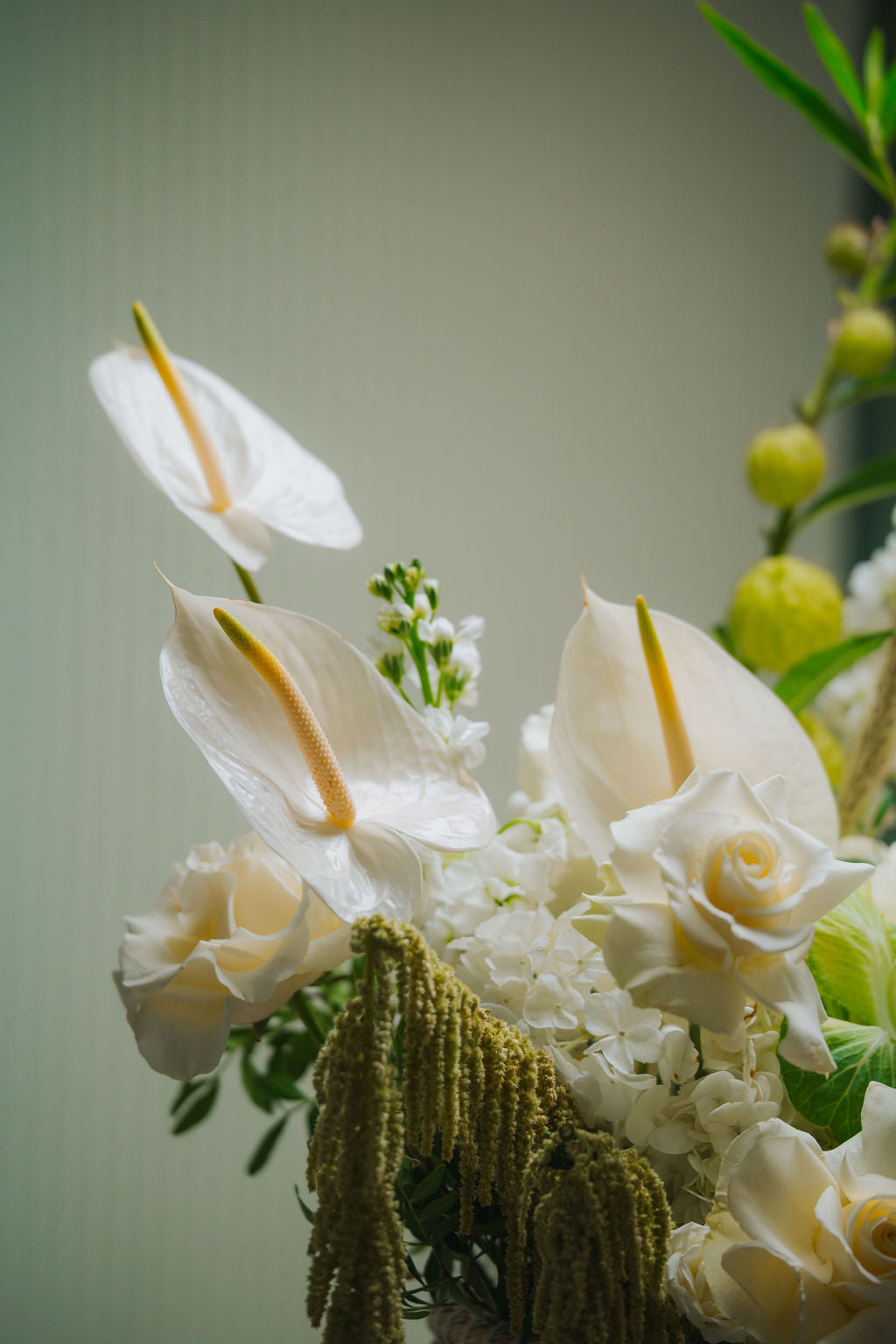 Luxury white floral basket with anthurium, roses, and textured greenery in a woven basket