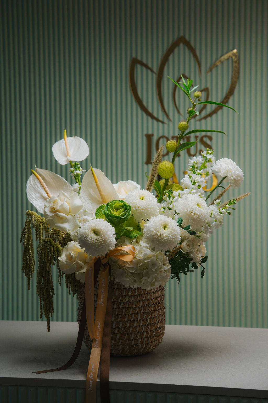 Luxury white floral basket with anthurium, roses, and textured greenery in a woven basket
