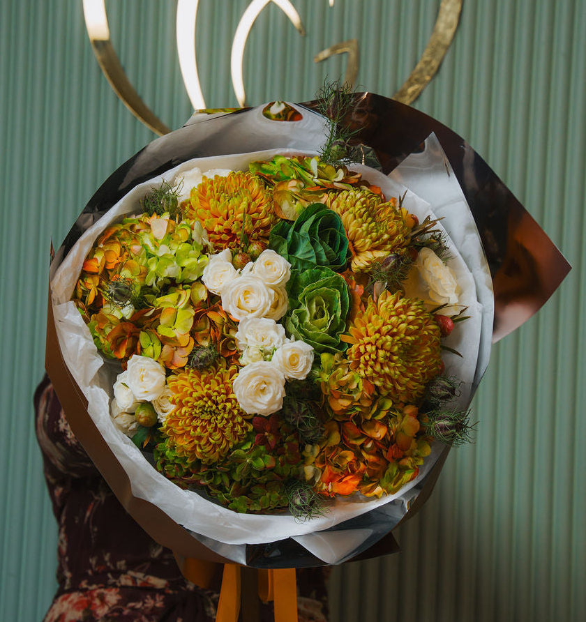 Luxury autumn bouquet with golden chrysanthemums, ivory roses, and brown wrapping