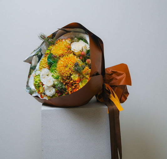 Luxury autumn bouquet with golden chrysanthemums, ivory roses, and brown wrapping 