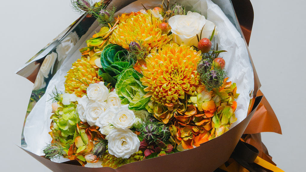 Luxury autumn bouquet with golden chrysanthemums, ivory roses, and brown wrapping by Lotus Land