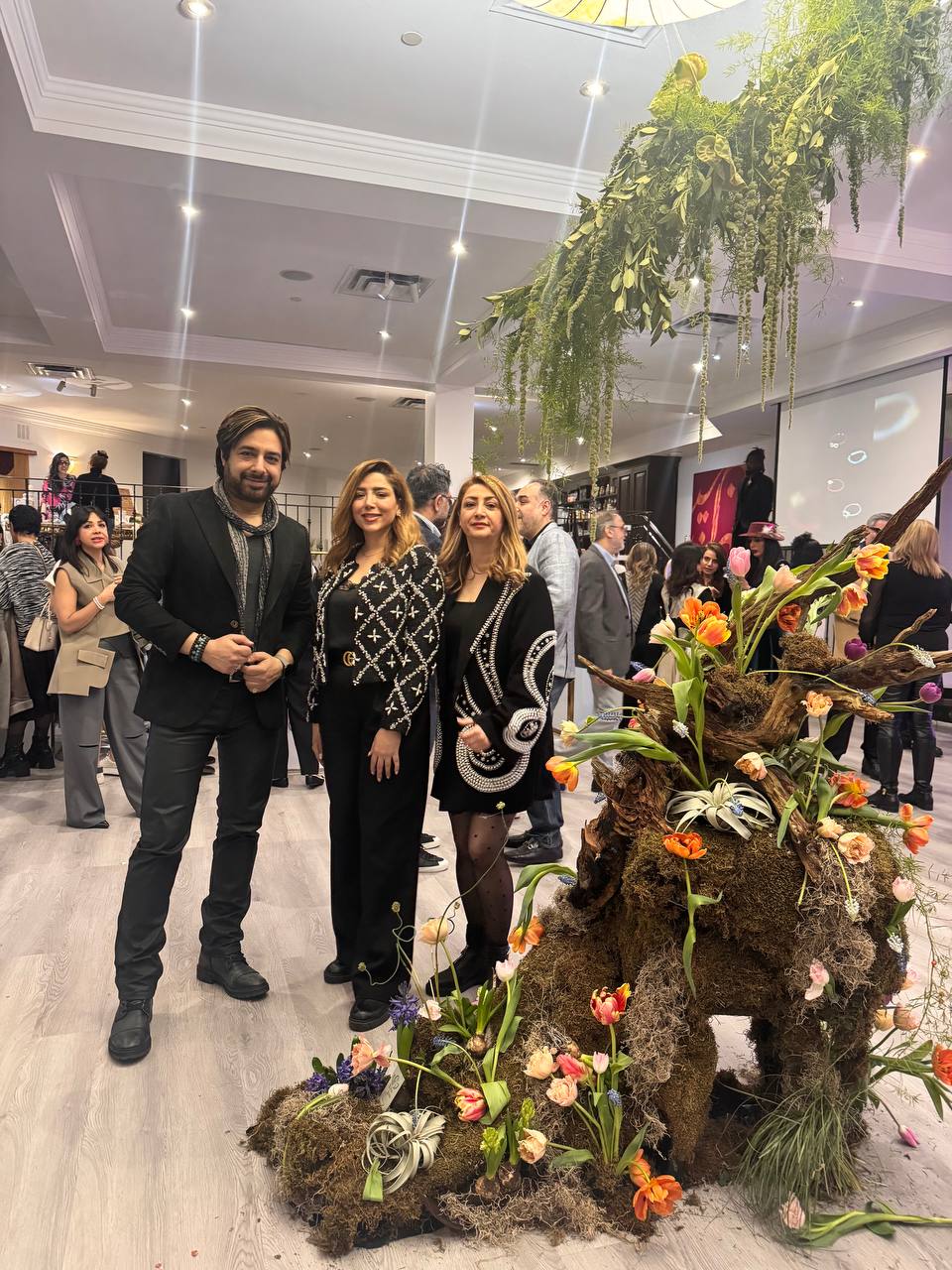 Persian-inspired moss and tulip floral structure displayed at the Raavi Art Event in Toronto, with a guest beside the installation
